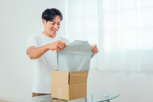 ダンボールから服を出す男性